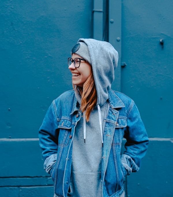 Woman smiling in a denim jacket over a hoodie